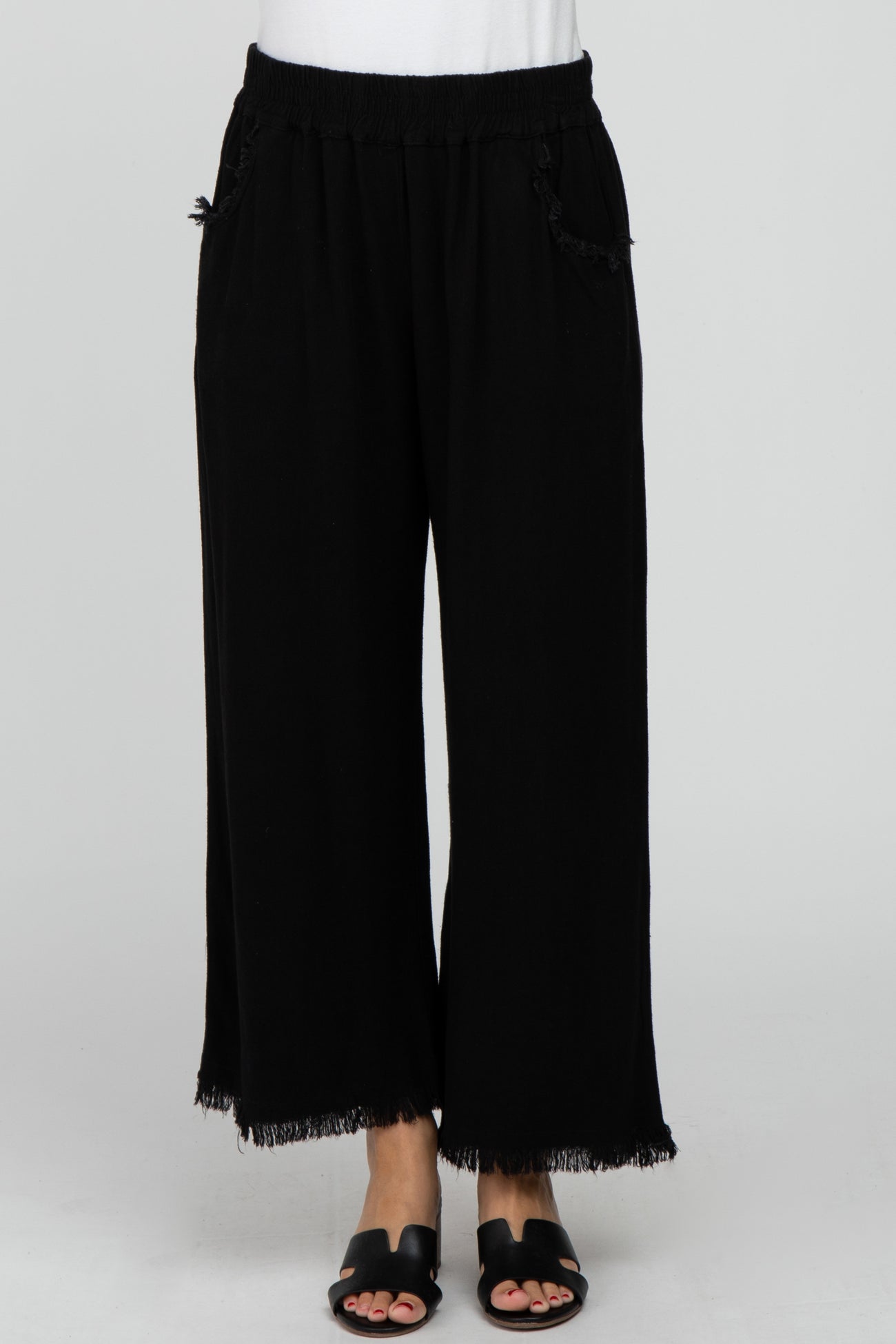 woman wearing black wide-leg pants with fringe hems and side pockets, styled with a simple white top