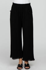 woman wearing black wide-leg pants with fringe hems and side pockets, styled with a simple white top