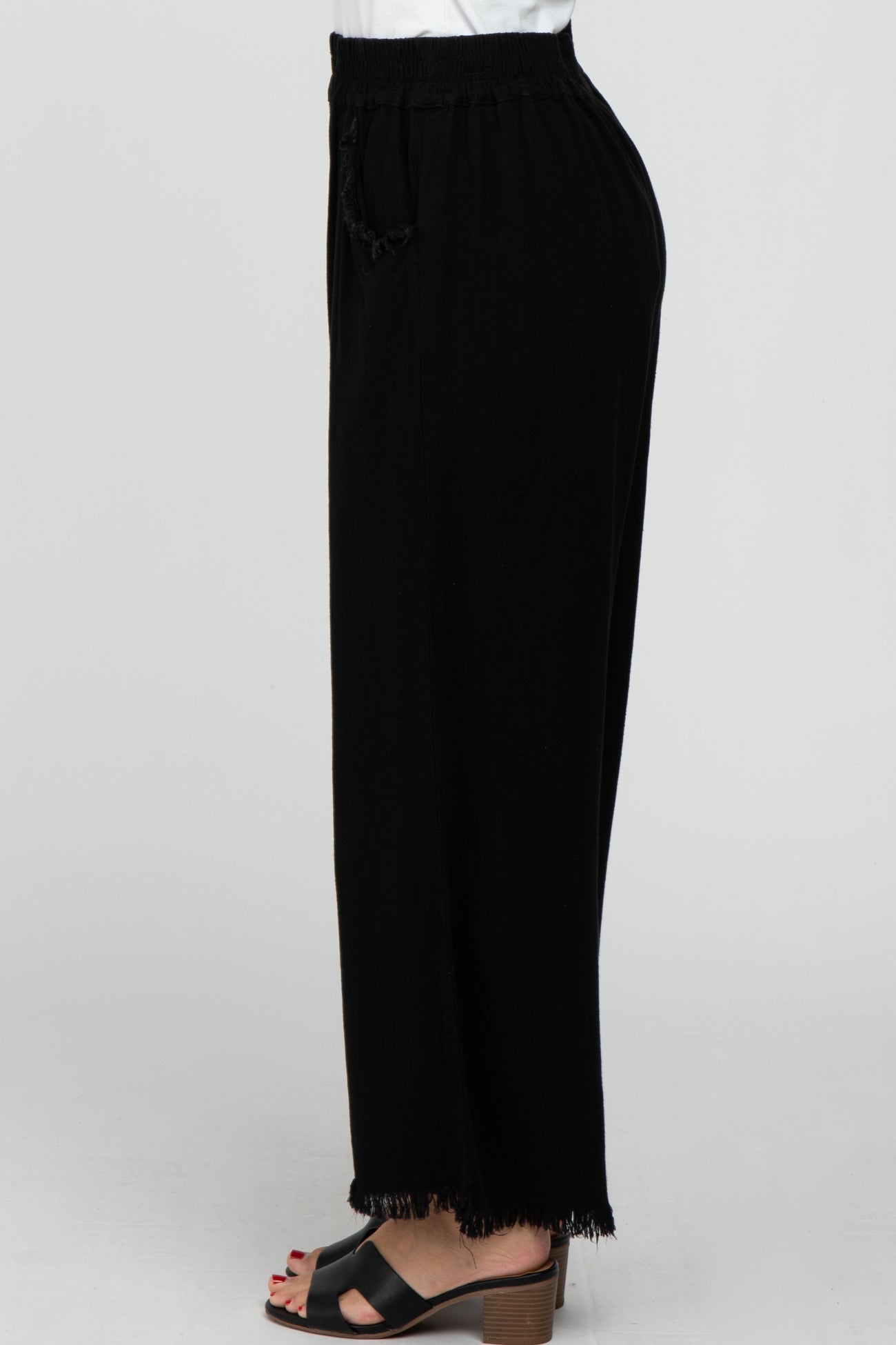 woman wearing black wide-leg pants with a drawstring waist and fringe detail at the hem