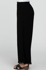 woman wearing black wide-leg pants with a drawstring waist and fringe detail at the hem