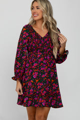 Woman wearing a long sleeve floral maternity dress with pink and orange flowers and smocked bodice