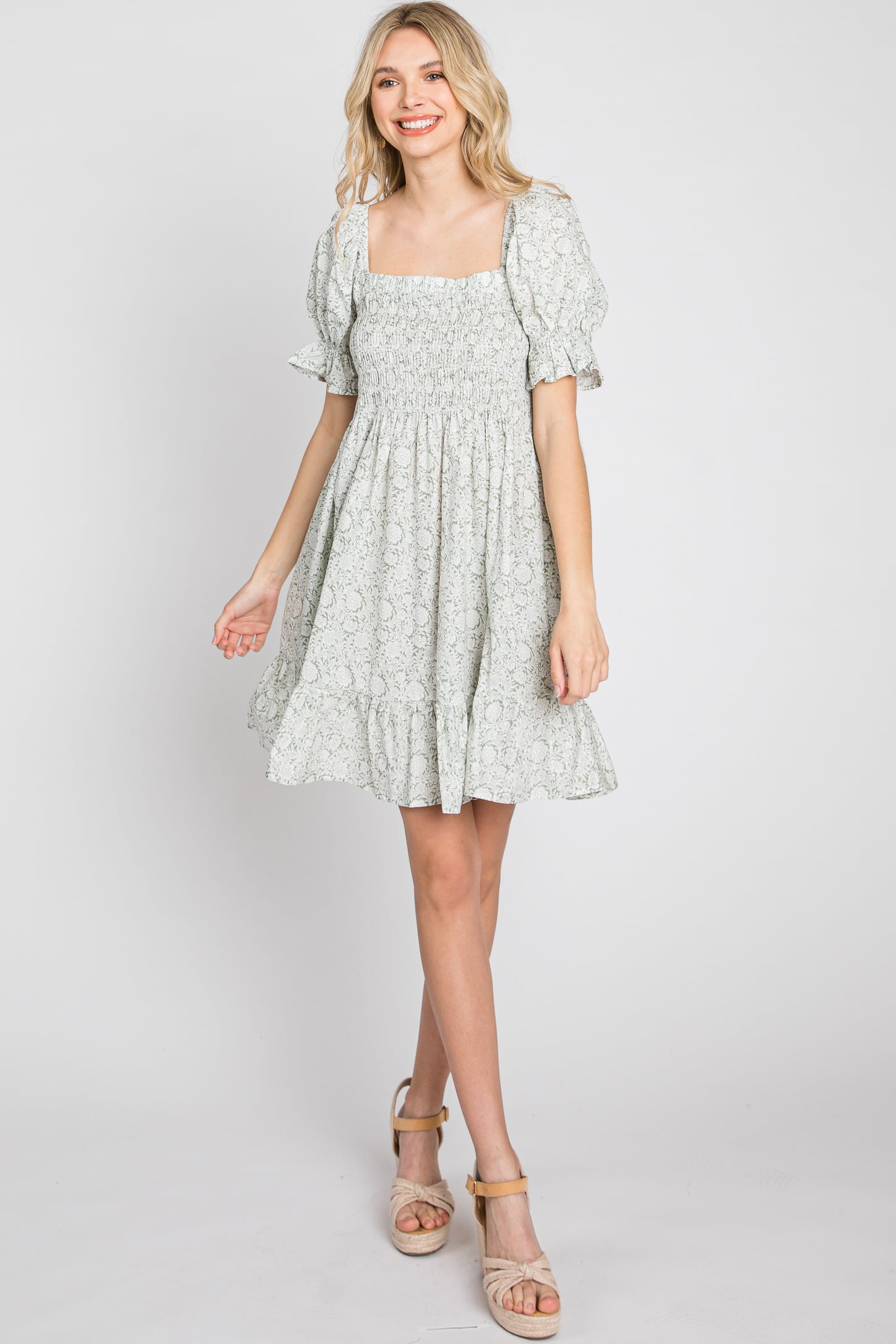 woman wearing a sage green floral smocked mini dress with puff sleeves and platform sandals
