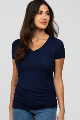 woman wearing a navy blue short sleeve v-neck top with ruching details, paired with blue jeans
