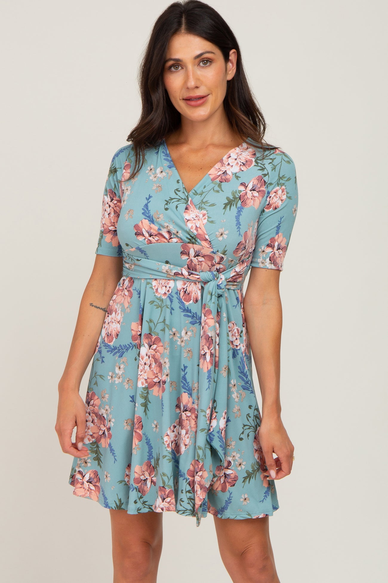 woman wearing a blue floral wrap dress with short sleeves and a tie waist detail