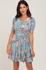 woman wearing a blue floral wrap dress with short sleeves and a tie waist detail