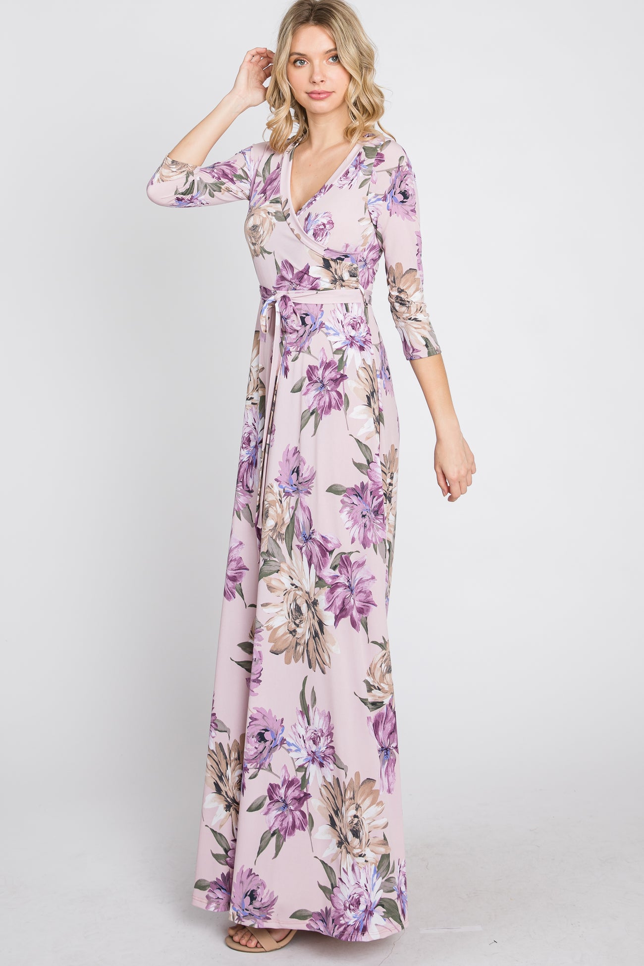 woman wearing a light pink floral print wrap maxi dress with three-quarter sleeves and a waist tie