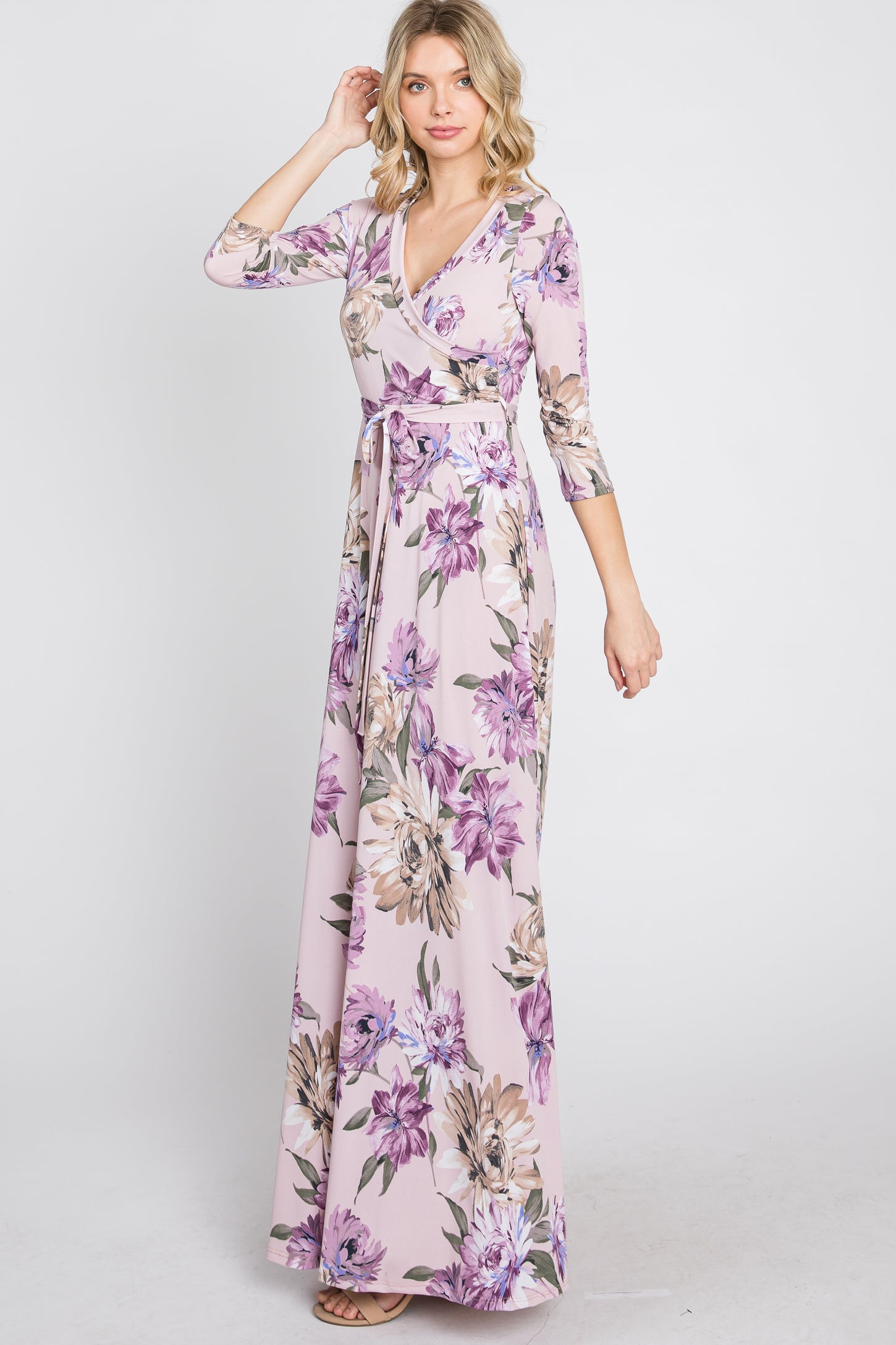 woman wearing a light pink floral print wrap maxi dress with three-quarter sleeves and a waist tie