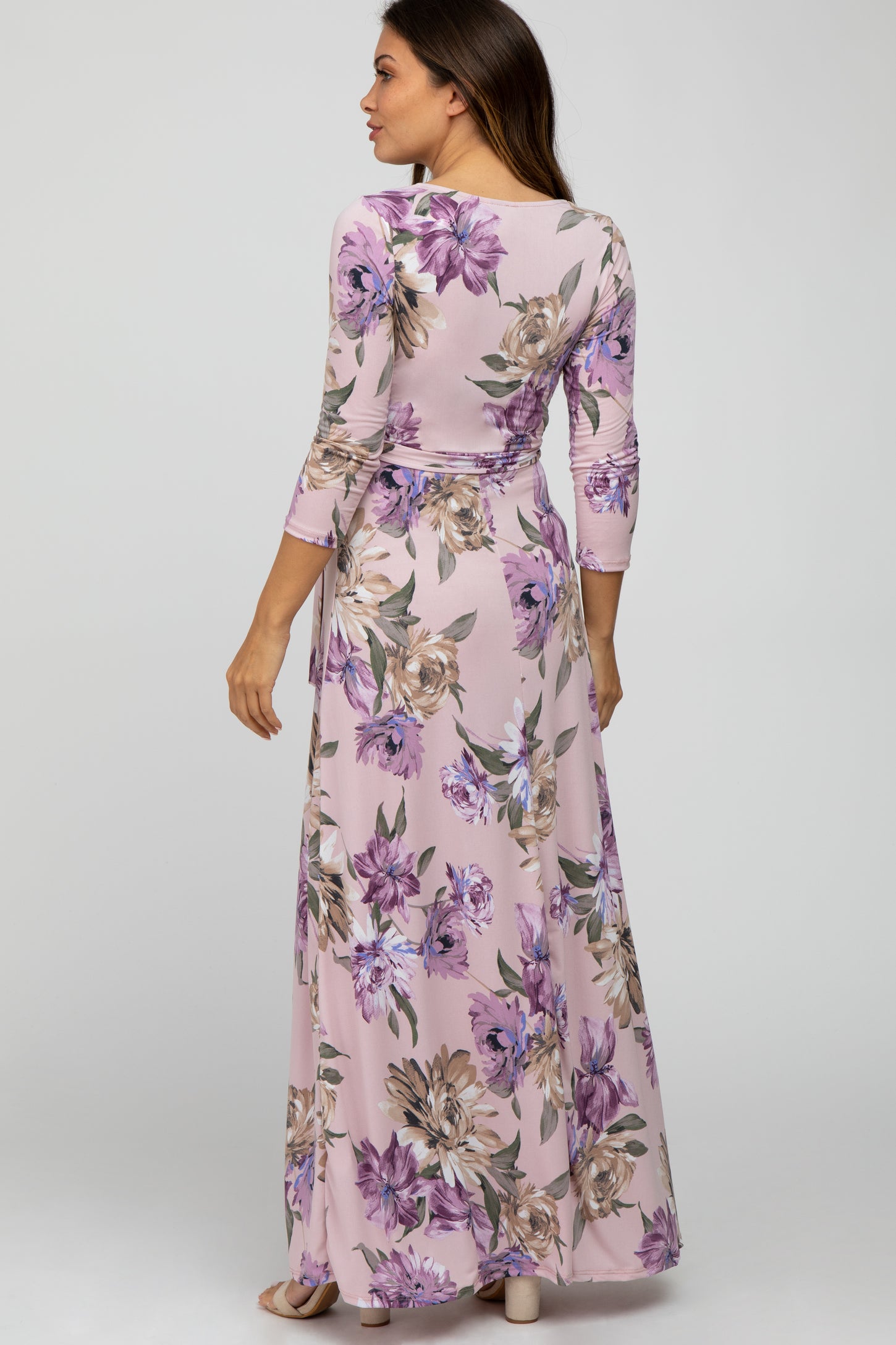 Woman wearing a light pink floral maternity maxi dress with purple flowers and three-quarter sleeves