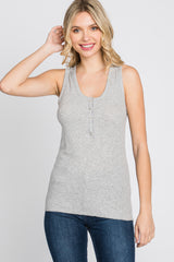 smiling woman wearing a grey ribbed henley tank top and blue jeans against a white background