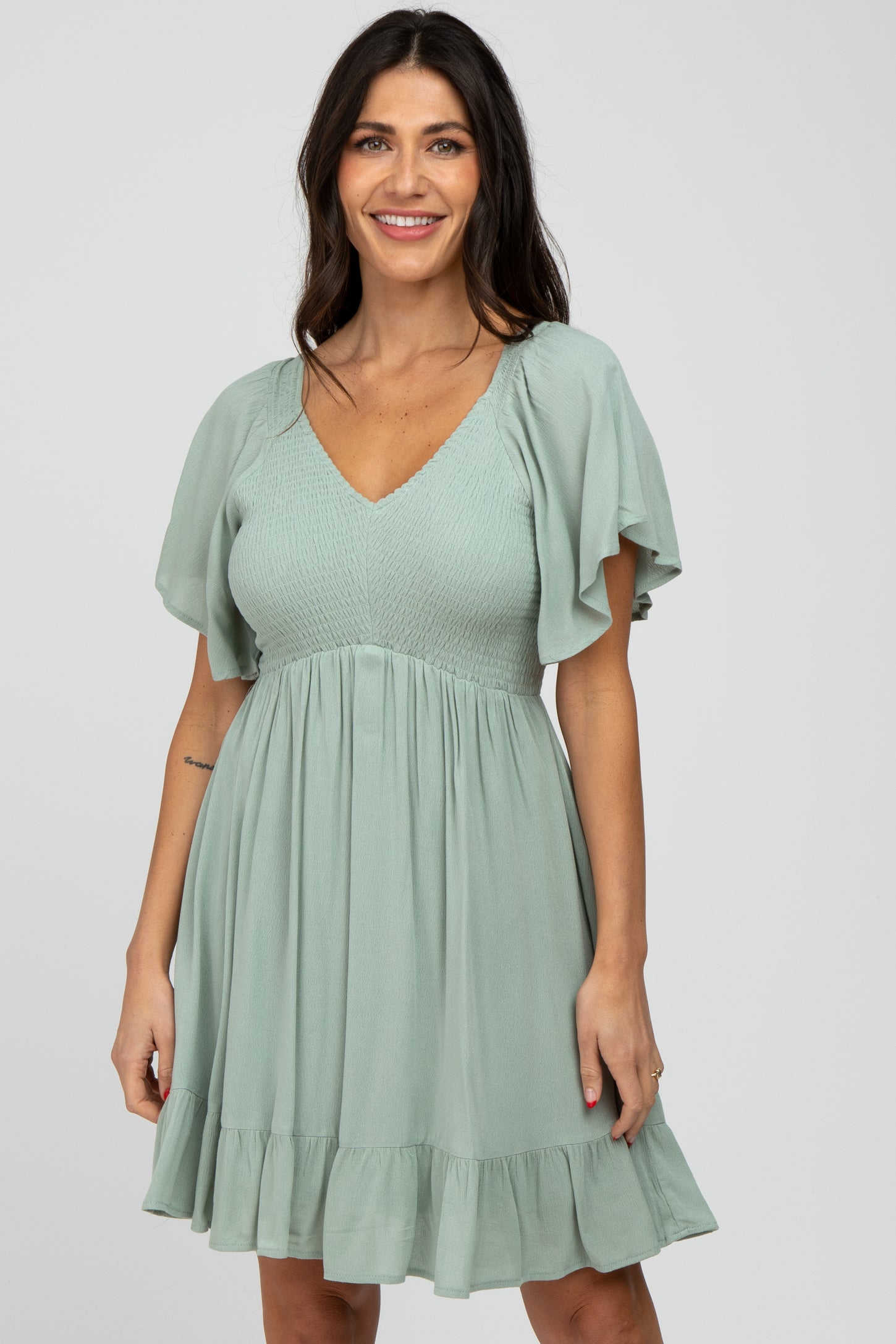 woman wearing a light green short sleeve dress with a v-neck and ruffle hem