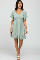 woman wearing a sage green v-neck maternity dress with flutter sleeves and a smocked bodice