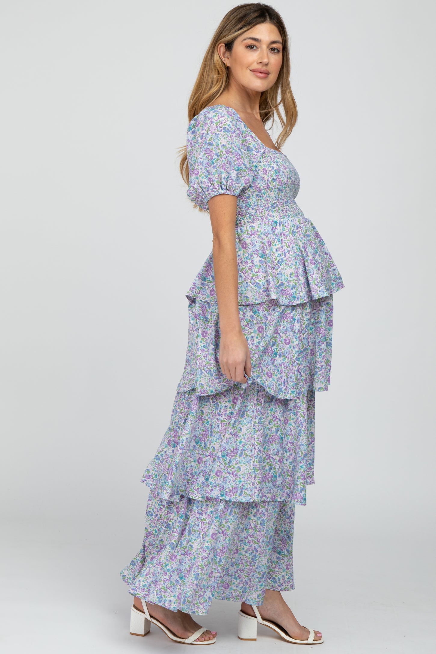 Pregnant woman in a tiered purple floral maternity maxi dress with puff sleeves and smocked bodice