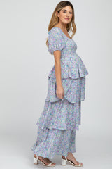 Pregnant woman in a tiered purple floral maternity maxi dress with puff sleeves and smocked bodice