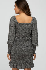 Woman wearing a black and white spotted long sleeve smocked dress with a square neckline and ruffled hem