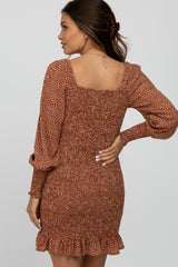 woman wearing a rust colored maternity dress with a square neckline, long sleeves, and ruffle hem.
