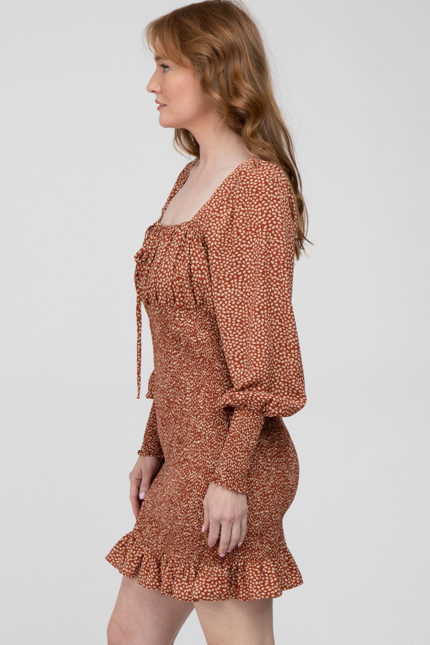 woman wearing a brown floral print mini dress with puff sleeves and a ruffled hem