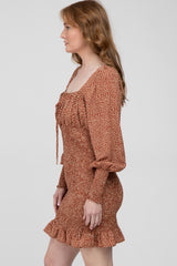 woman wearing a brown floral print mini dress with puff sleeves and a ruffled hem