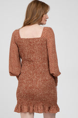 woman wearing a rust-colored floral mini dress with a square neckline and ruffle hem, seen from the back