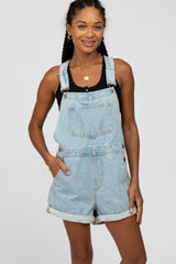 woman wearing light blue denim overalls with rolled-up hems and a black tank top underneath