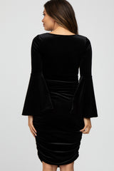 Back view of a woman wearing a black velvet bodycon dress with long bell sleeves and ruched detailing