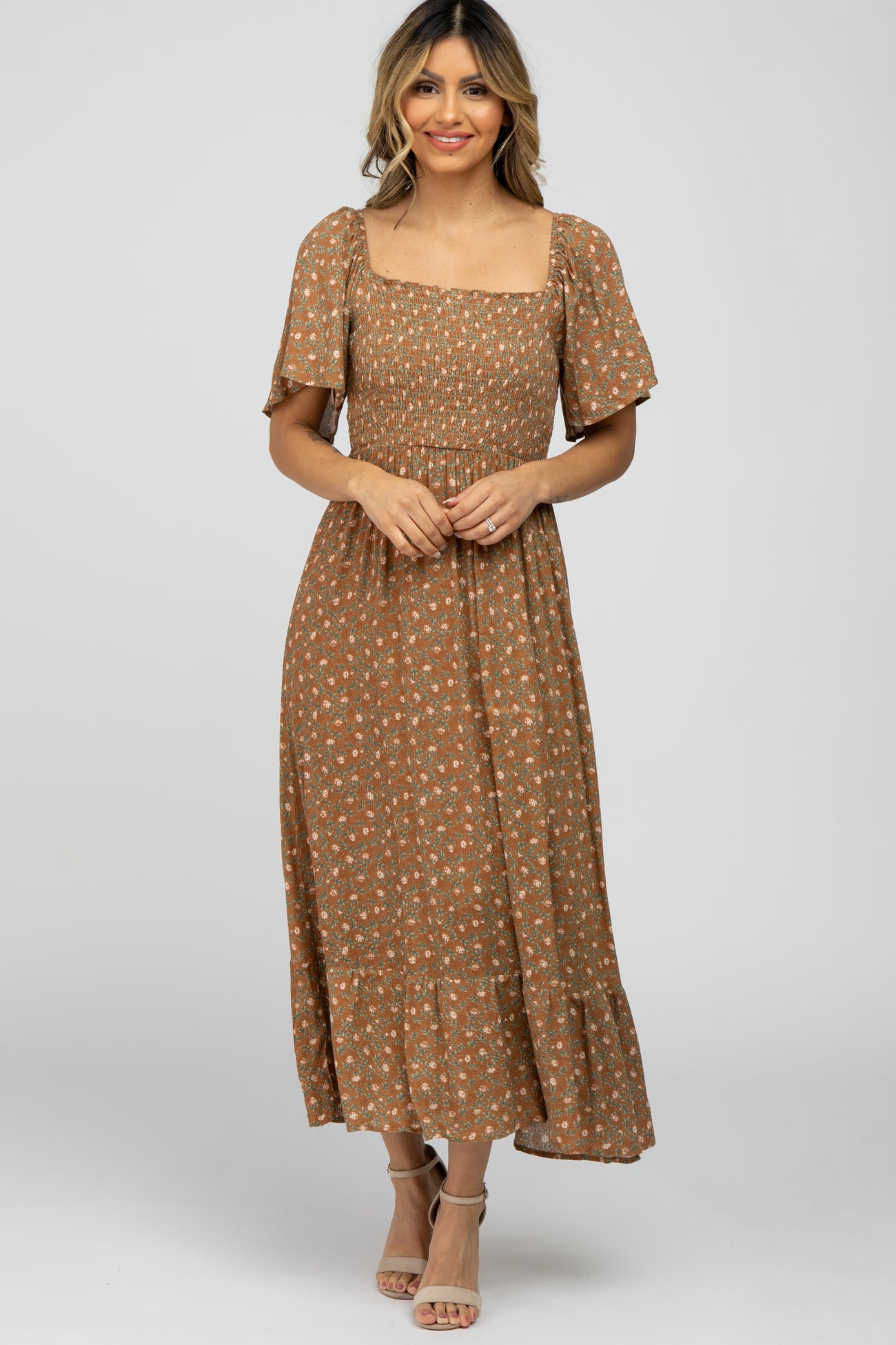 woman wearing a brown floral smocked midi dress with flutter sleeves and square neckline