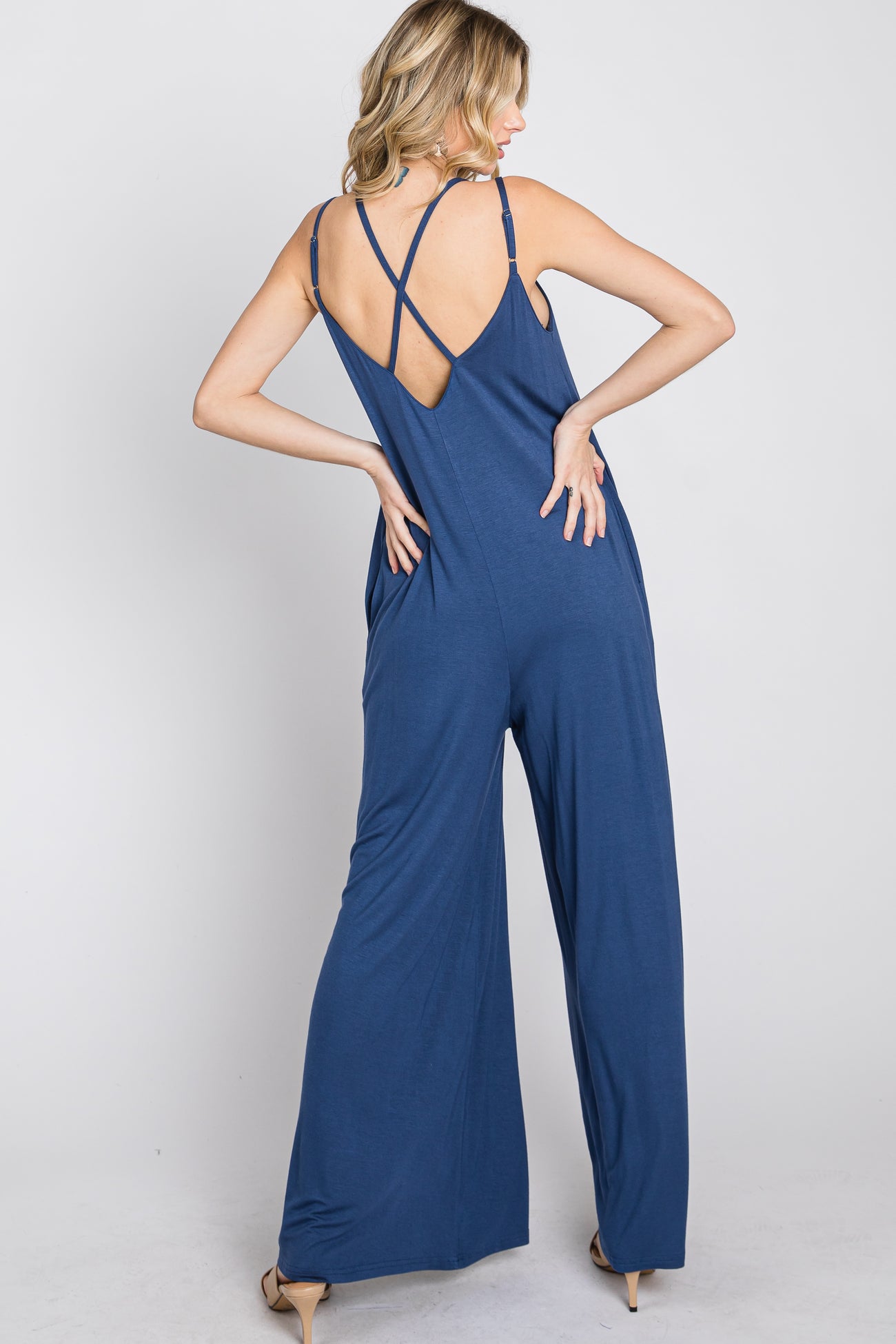 woman wearing a navy blue sleeveless jumpsuit with crisscross back straps and wide legs