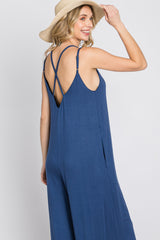woman wearing a navy blue sleeveless jumpsuit with a crisscross back design and a wide leg silhouette