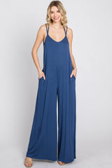 woman wearing a navy blue sleeveless jumpsuit with wide legs and side pockets