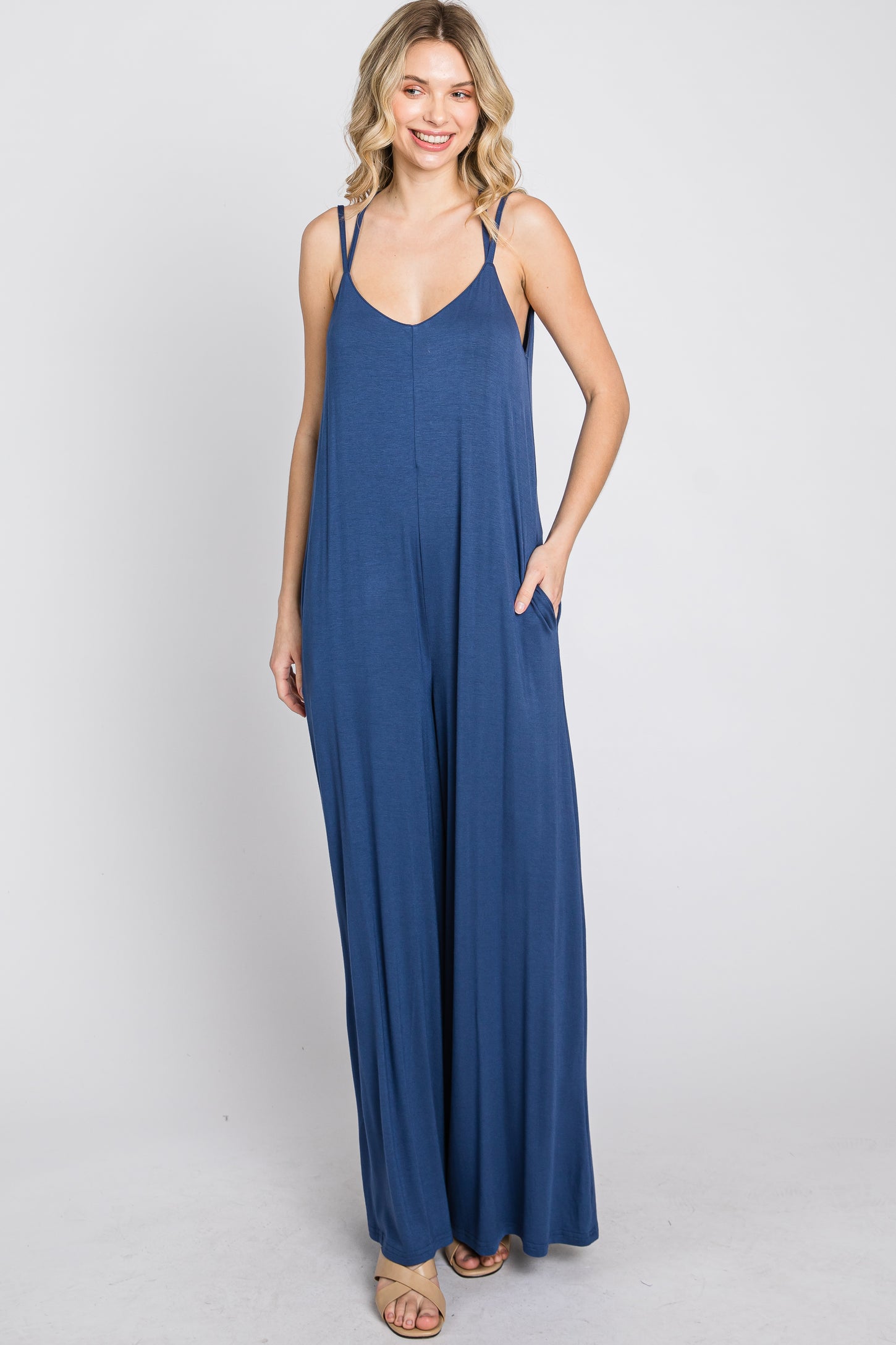 woman wearing a navy blue sleeveless jumpsuit with a relaxed fit and side pockets