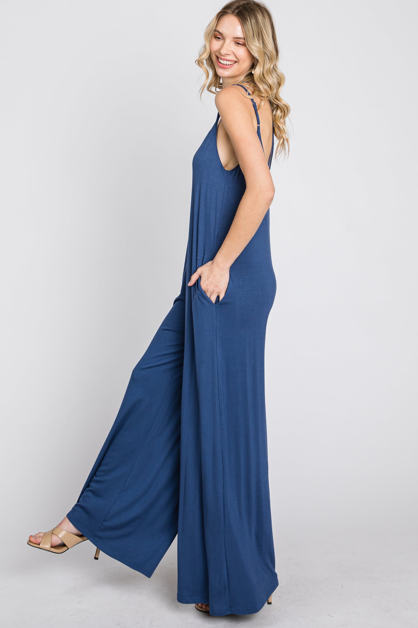 woman wearing a navy blue sleeveless jumpsuit with side pockets and a relaxed fit