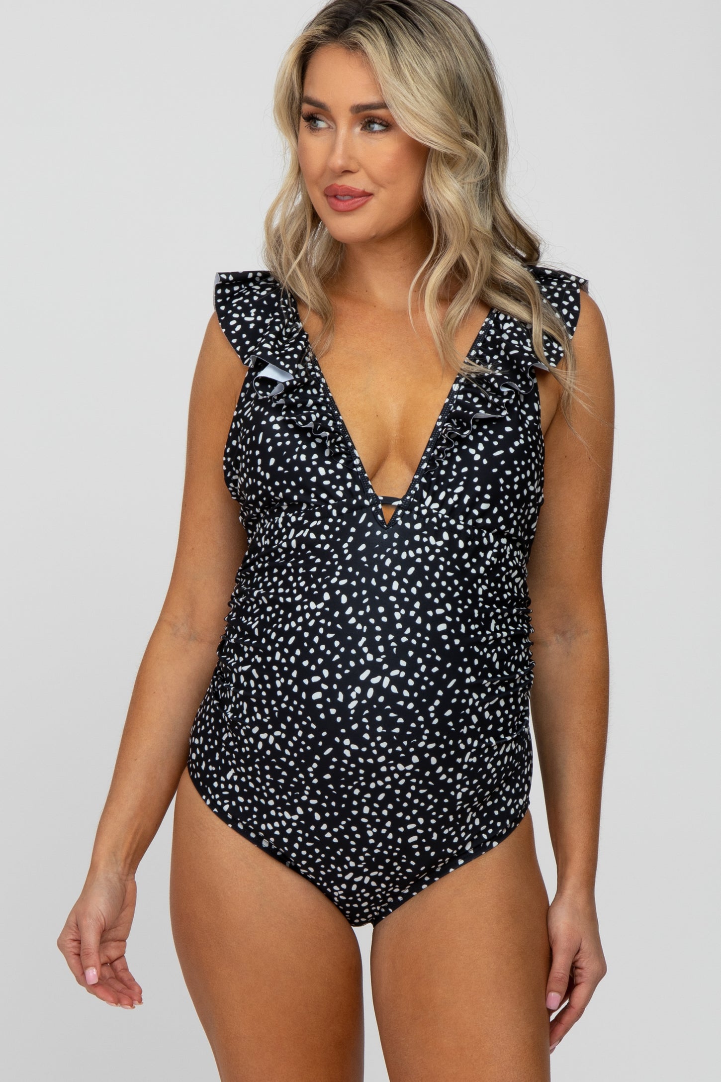 woman wearing a black and white polka dot maternity one piece swimsuit with ruffle sleeves