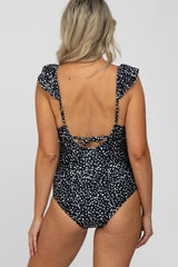 woman wearing a black polka dot maternity swimsuit with ruffle straps and crisscross back detailing