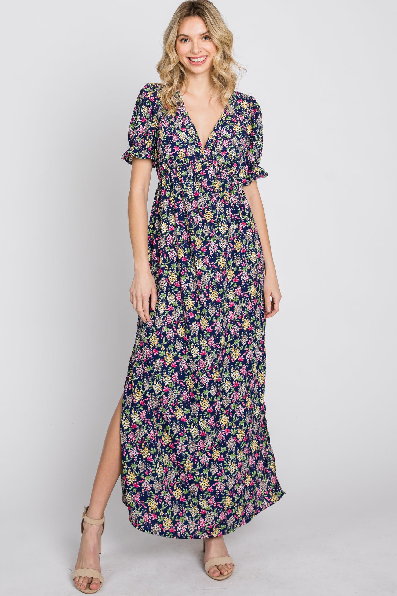 woman wearing a navy blue floral print maxi dress with short puff sleeves and a side slit