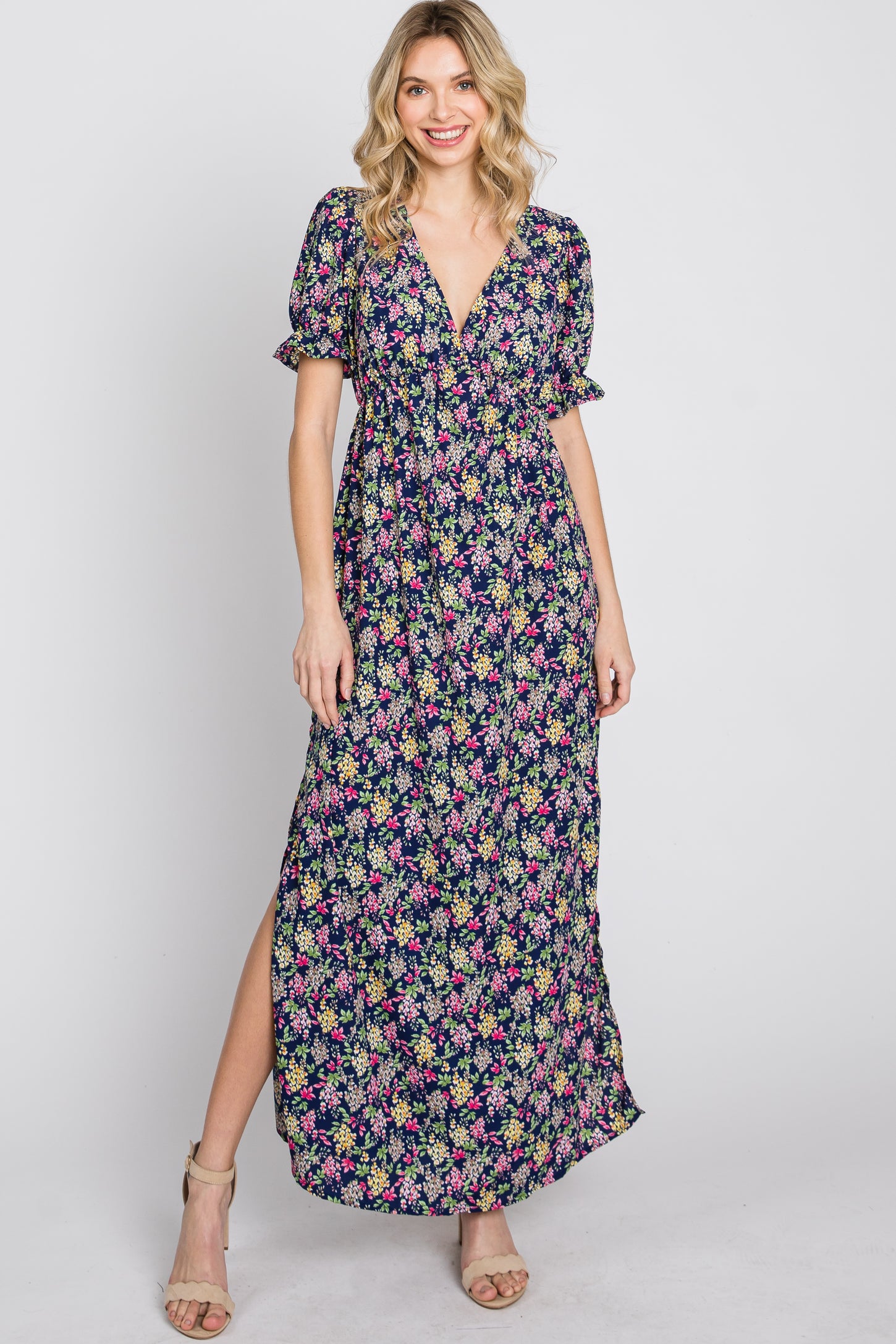 woman wearing a navy blue floral print maxi dress with short puff sleeves and a side slit