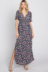 woman wearing a navy blue floral print maxi dress with short puff sleeves and a side slit