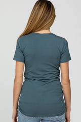 woman wearing a teal maternity top, showing the back view with a fitted design and ruching details