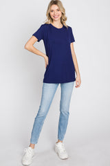 woman wearing a navy blue short sleeve t-shirt and light blue jeans, standing with one hand on her hip