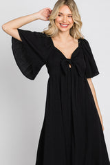 woman wearing a black short sleeve maxi dress with a tie front and flared sleeves