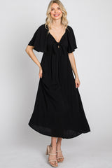 woman wearing a black maxi dress with flutter sleeves and a tie front detail