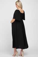 woman wearing a black polka dot maternity dress with short sleeves, showing her baby bump from the back