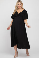woman wearing a black maternity maxi dress with short sleeves and a front tie, showing her baby bump