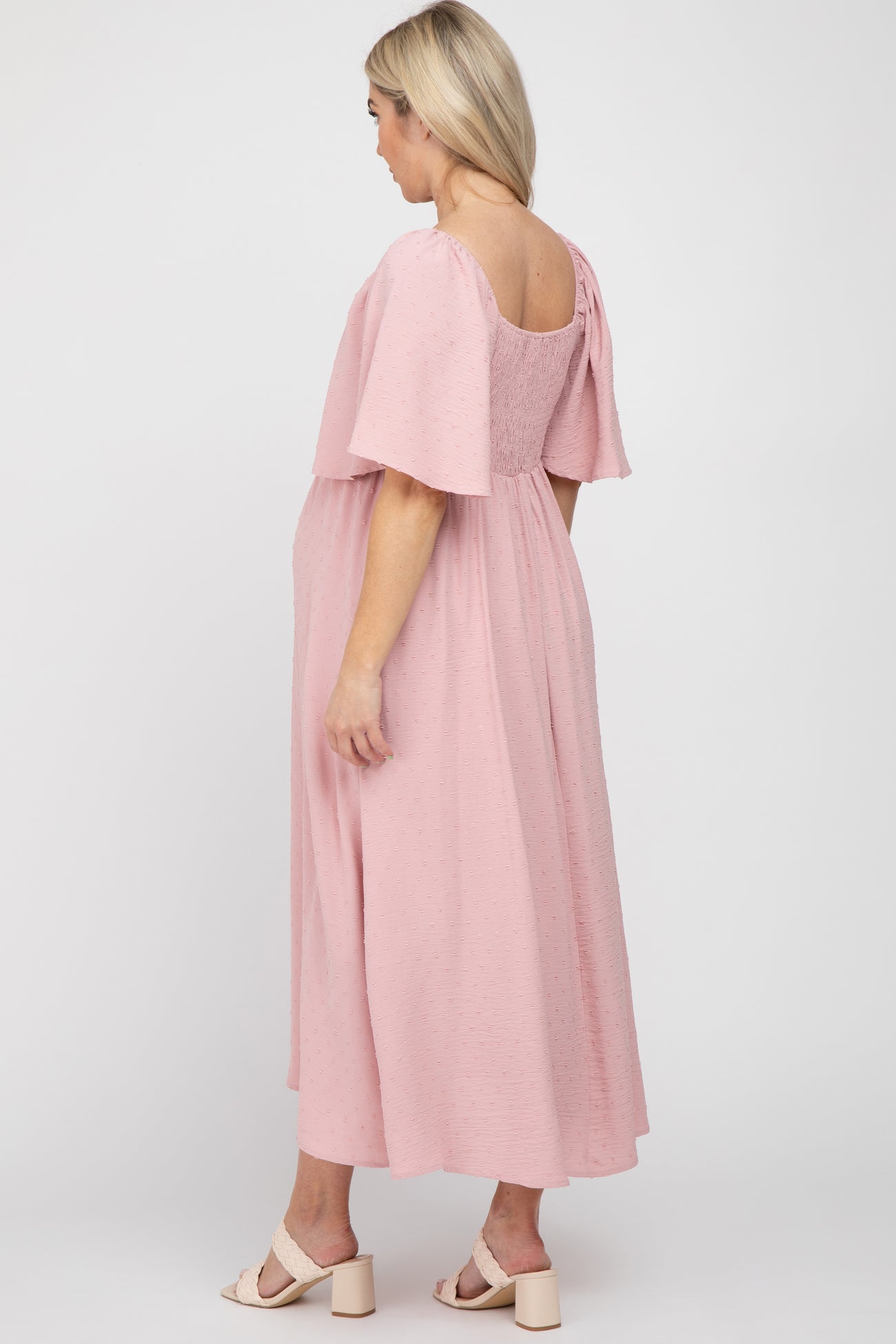 woman wearing a pink maternity dress with flutter sleeves and a loose fit, showing her baby bump from the back
