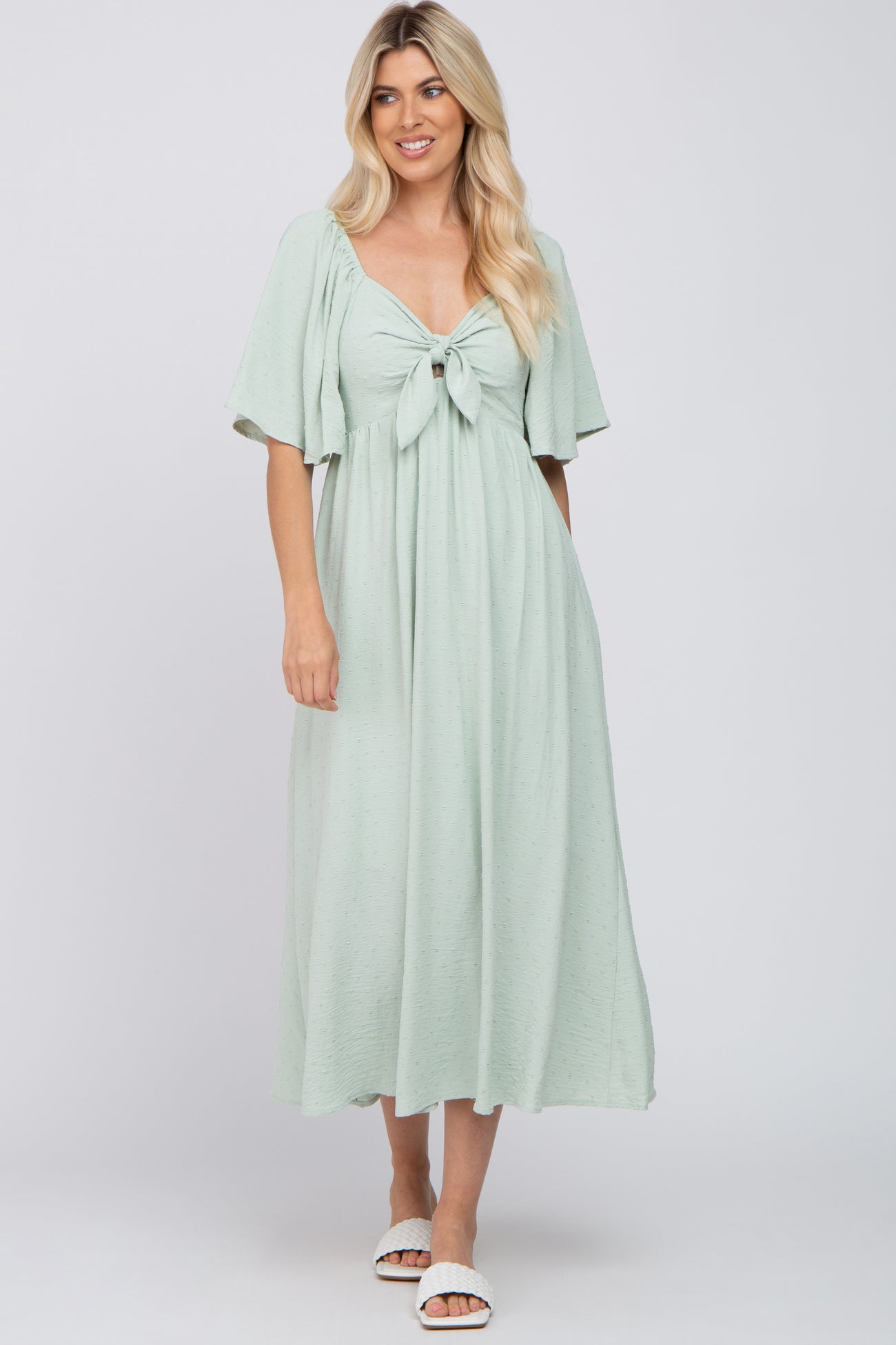 woman wearing a light green maxi dress with short sleeves and a front knot detail
