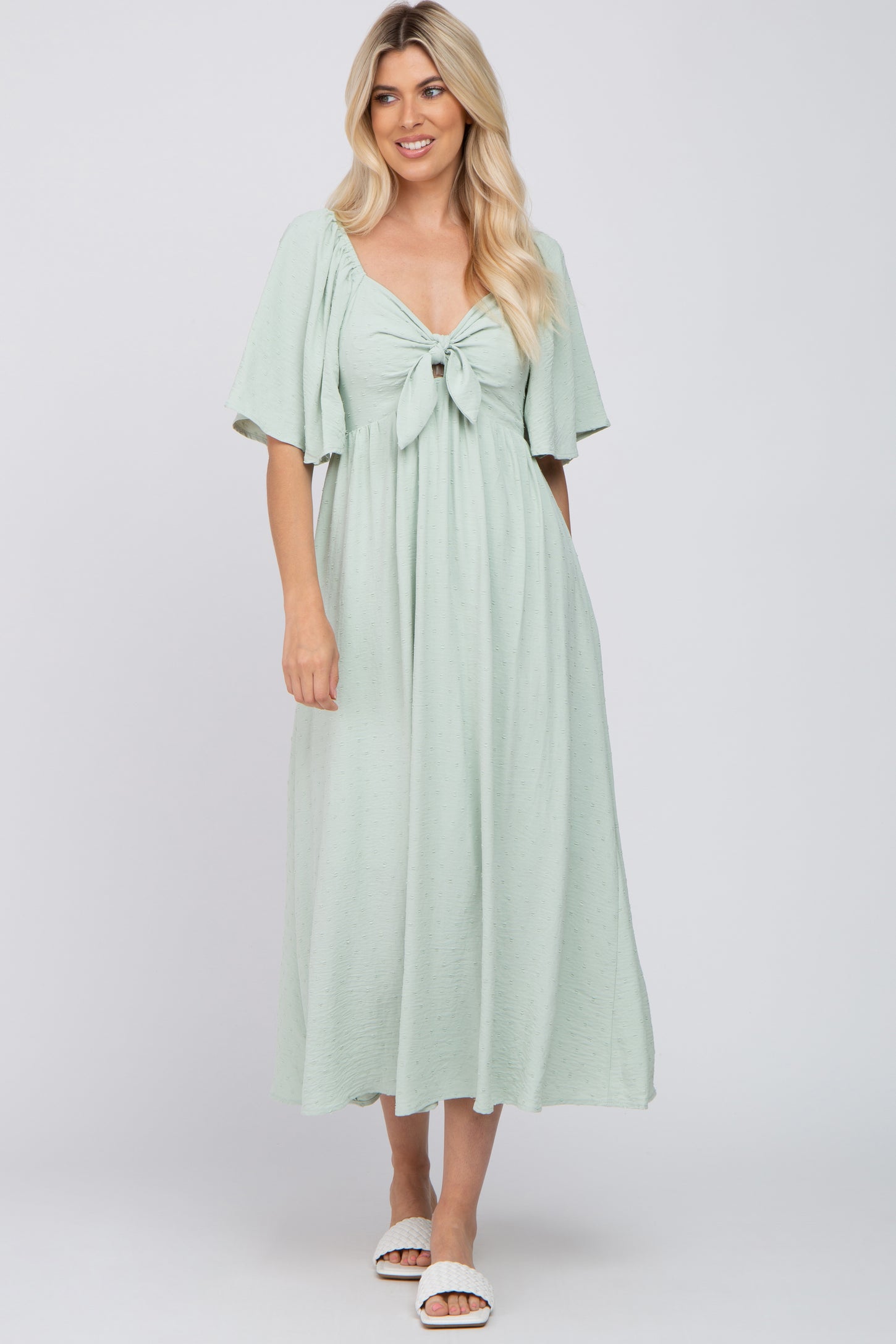 woman wearing a light green maxi dress with short sleeves and a front knot detail