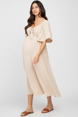 woman wearing a beige maternity dress with short sleeves and tie front detail, showing her baby bump