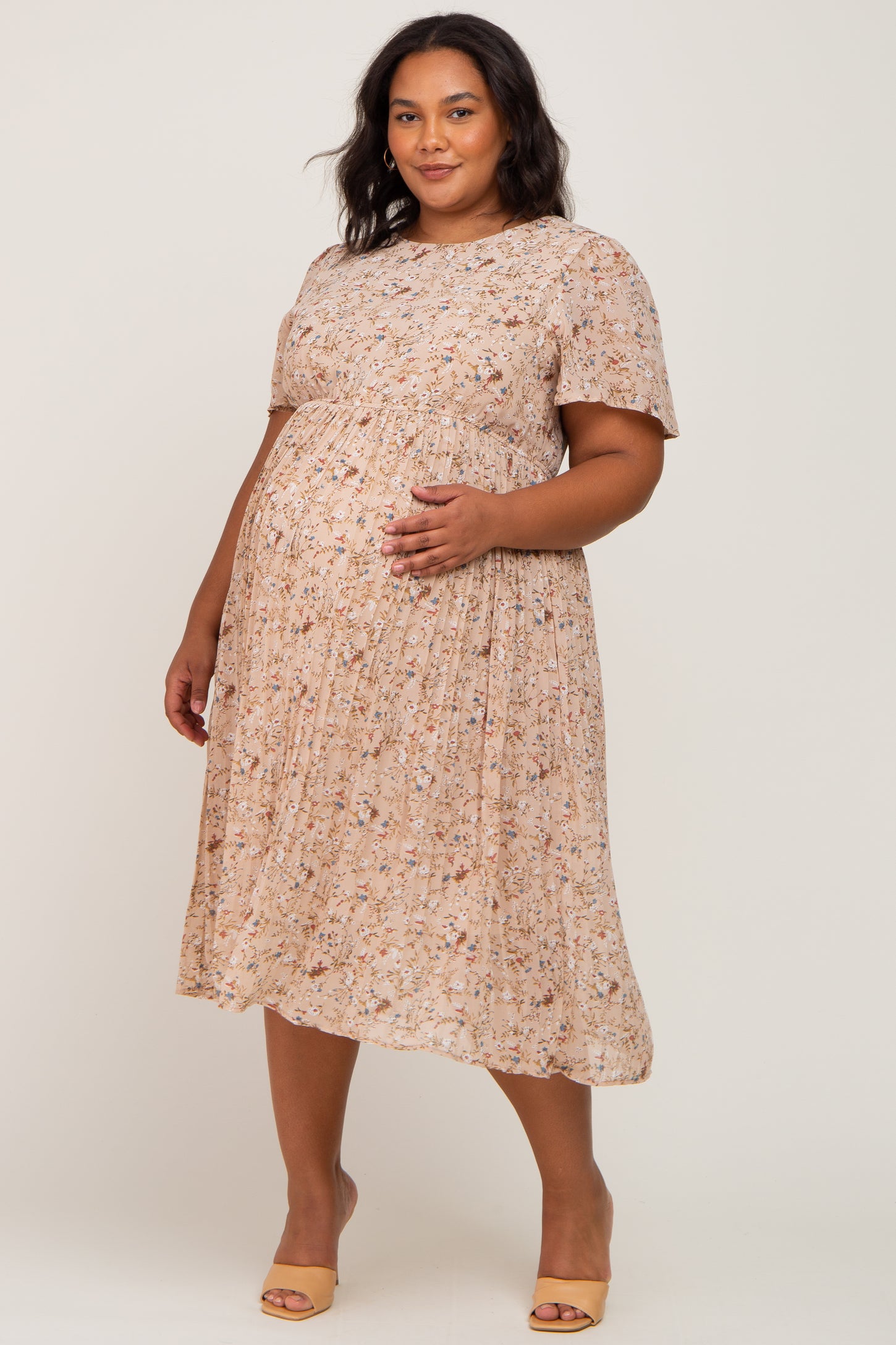 woman wearing a floral printed maternity plus dress with short sleeves and a visible baby bump