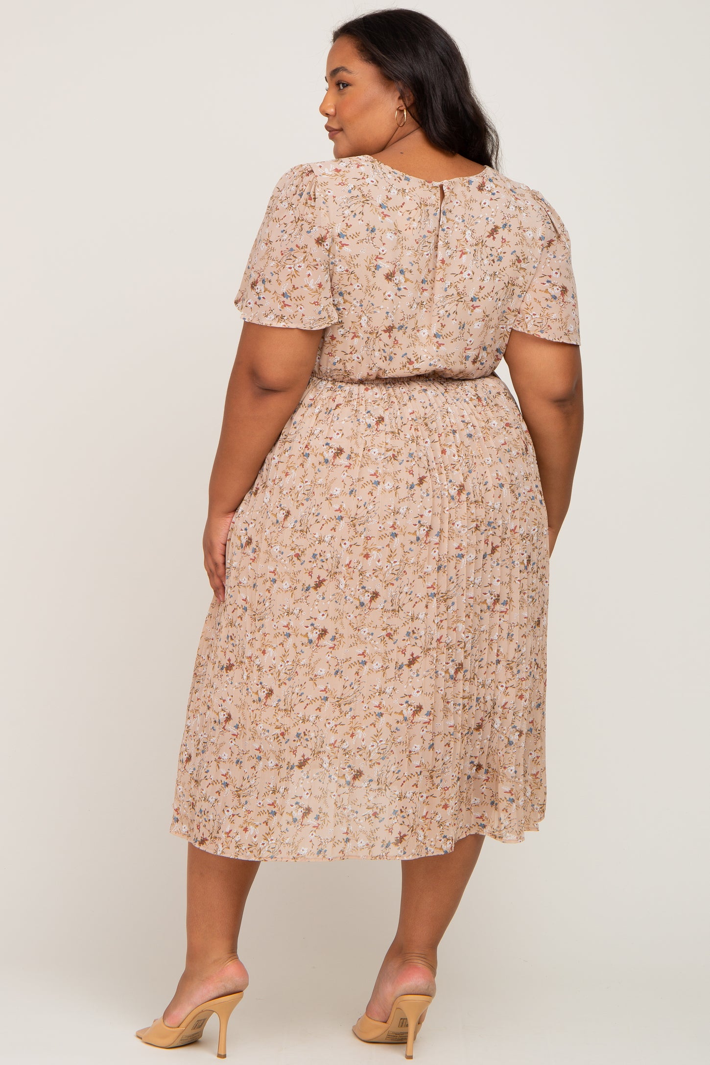 woman wearing a floral beige maternity plus dress with short sleeves and a cinched waist, showing the back view