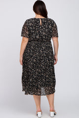back view of woman wearing plus size black floral pleated midi dress with short sleeves and white heels
