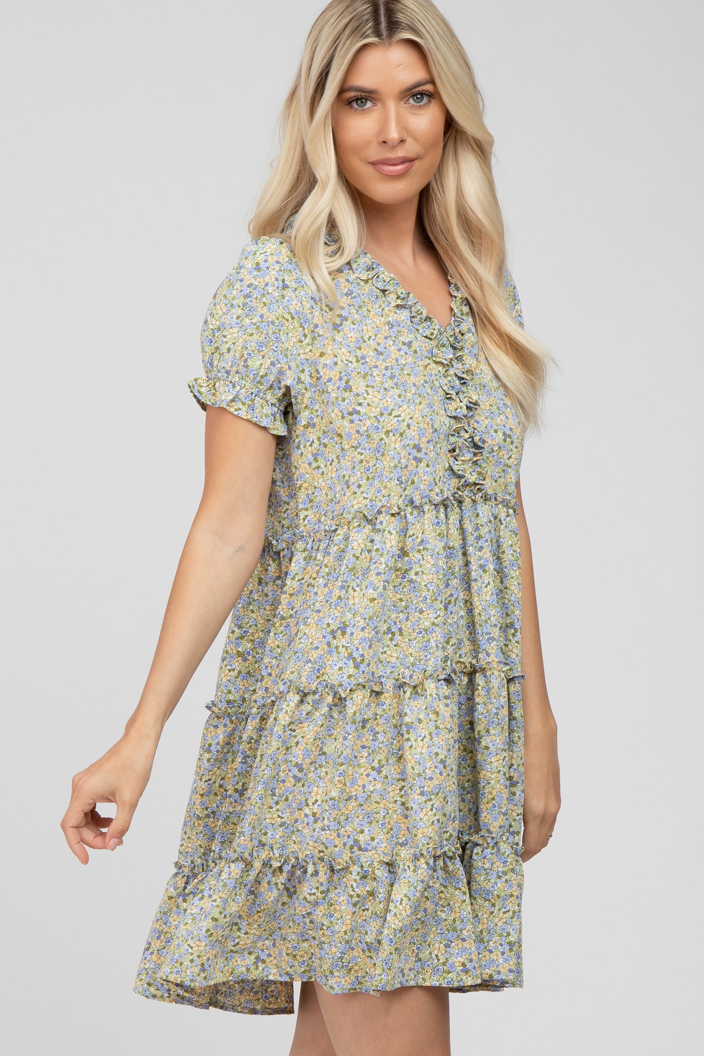 blonde woman wearing a short sleeve tiered floral mini dress with ruffle details