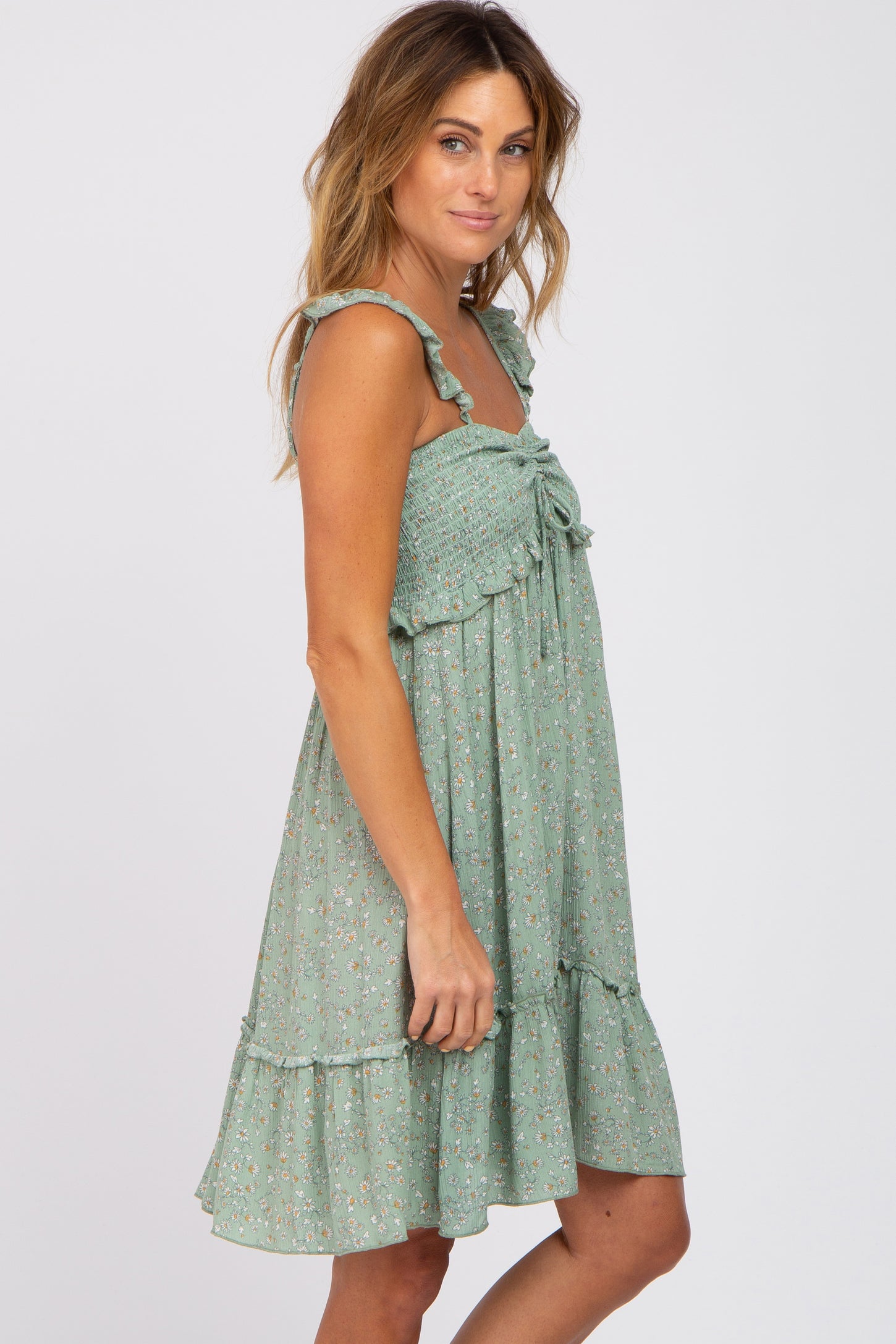 woman wearing a sage green floral smocked maternity dress with ruffle straps and a tiered skirt